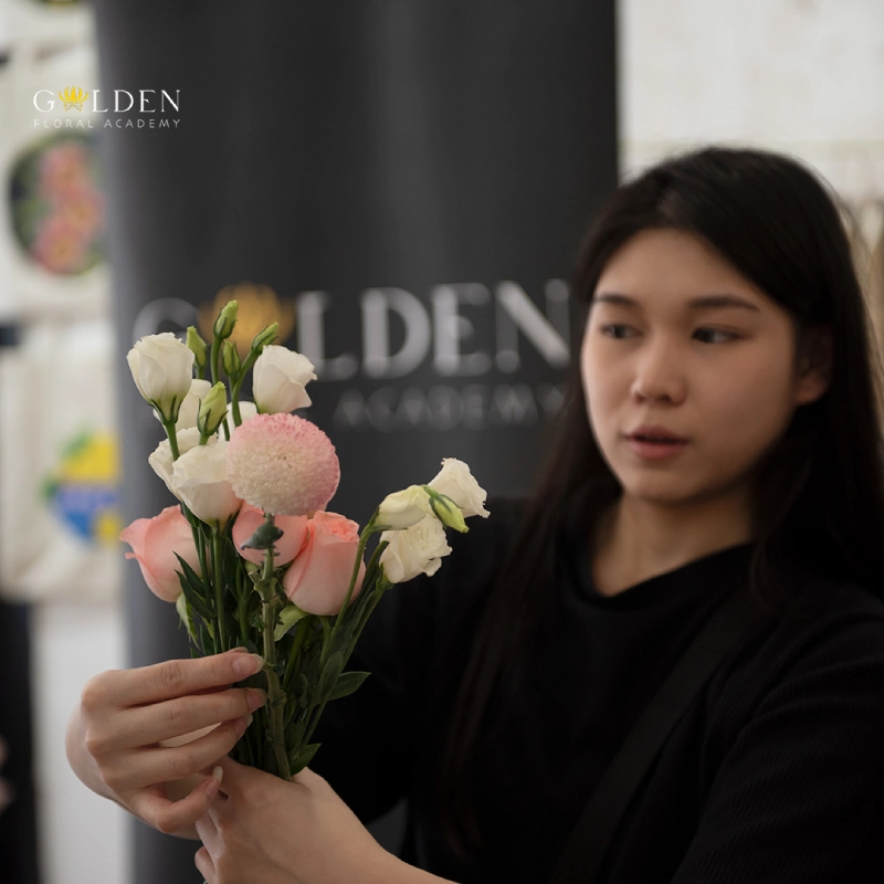 flower arranging workshop, florist is arranging flower stems in a flower workshop, flower arrangement class