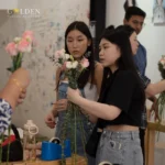 Girl florist is teaching asian girl while holding fresh flowers