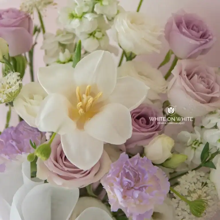 White flower bouquet with roses, orchids, and hydrangeas in soft pastel shades.