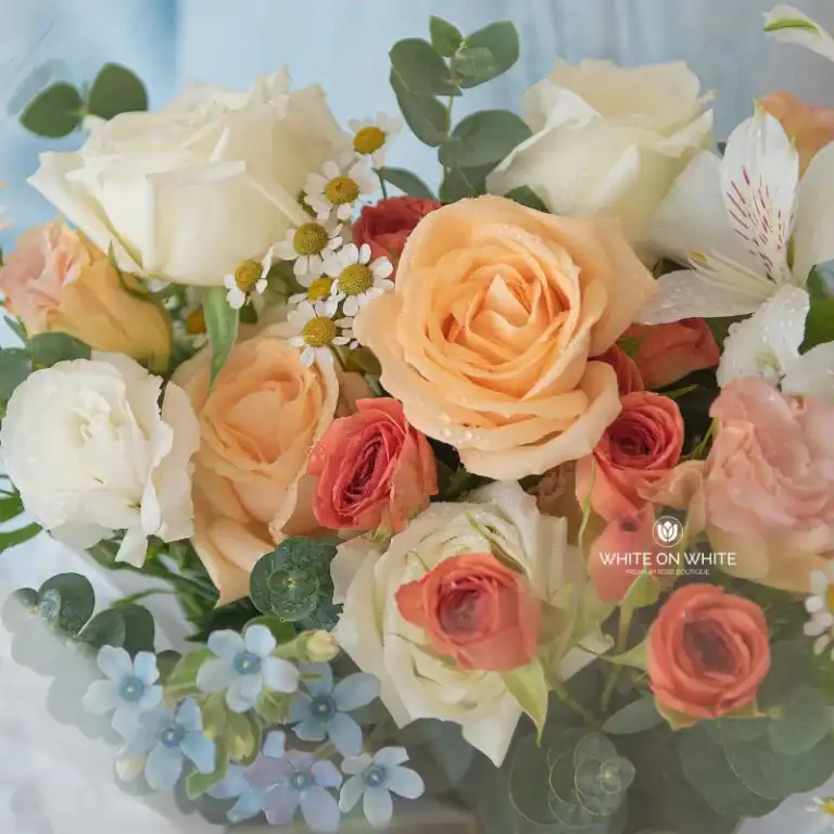 Elegant cream and peach roses with white daisies and greenery, perfect for weddings or special occasions.